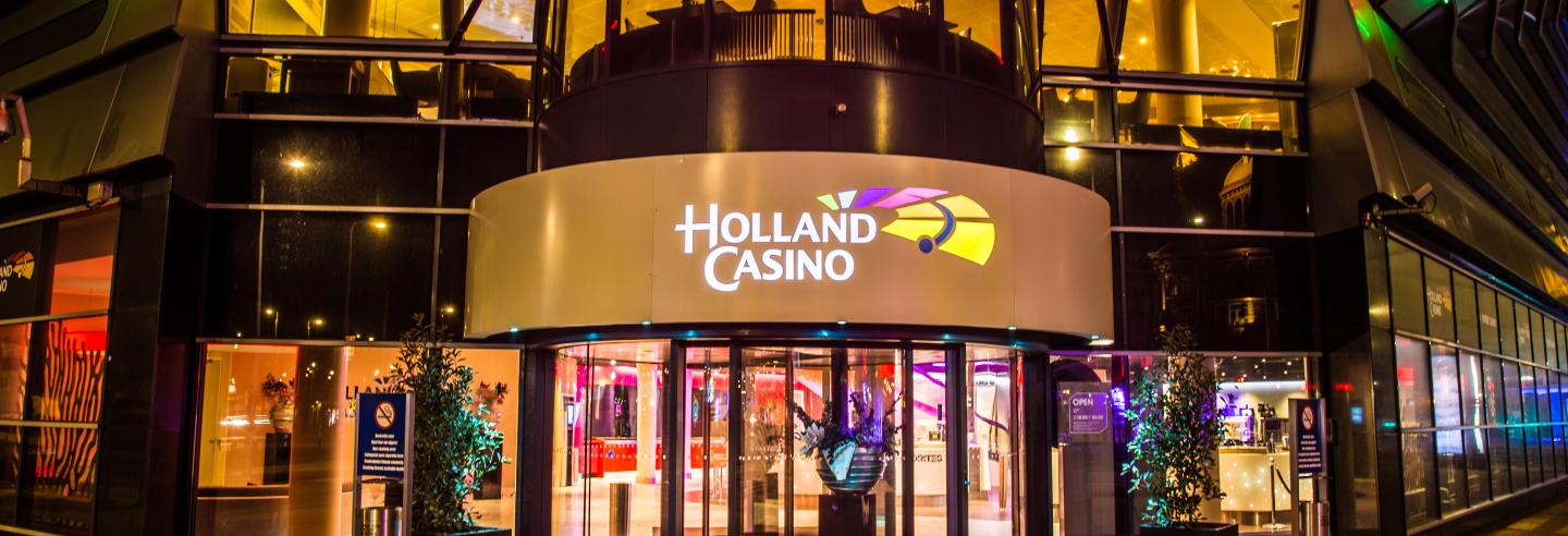 De voorkant van een Holland Casino waarbij je kijkt op de draaideur met daarboven het logo.