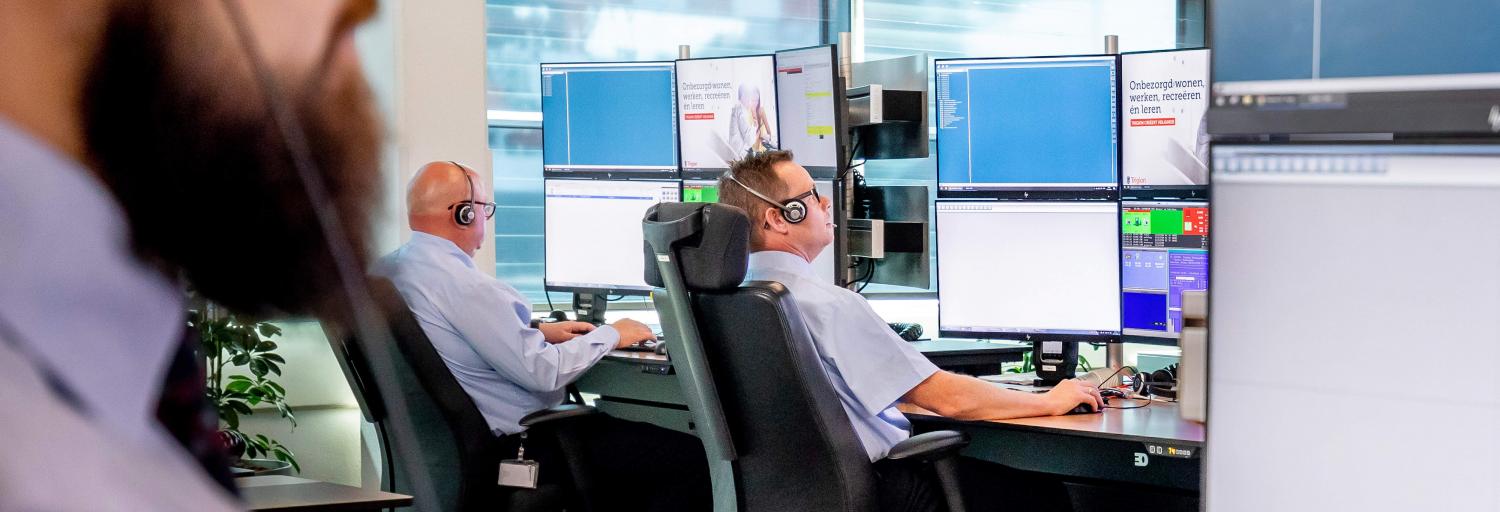 Drie mannelijke Trigion collega's die achter hun beeldschermen zitten om de situatie in de gaten te houden.