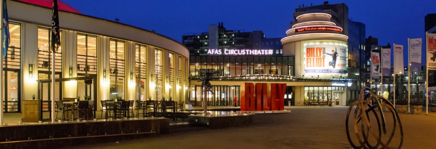 het Afas Circustheater in de avond met alle lichtjes aan en op het billboard de reclame voor de BIlly Elliot musical