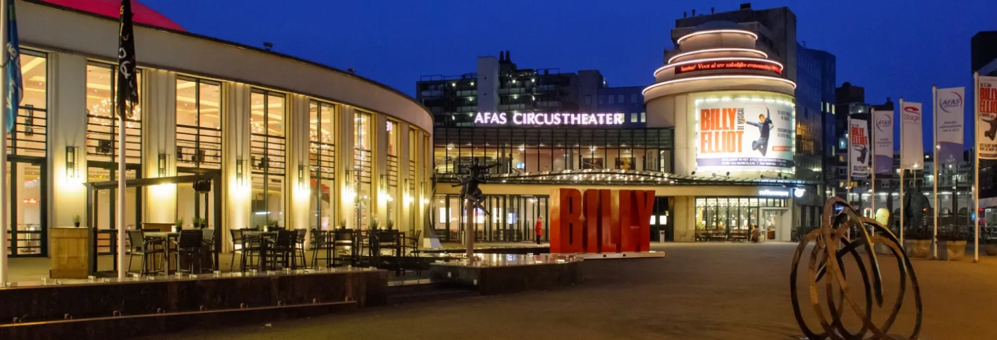 het Afas Circustheater in de avond met alle lichtjes aan en op het billboard de reclame voor de BIlly Elliot musical