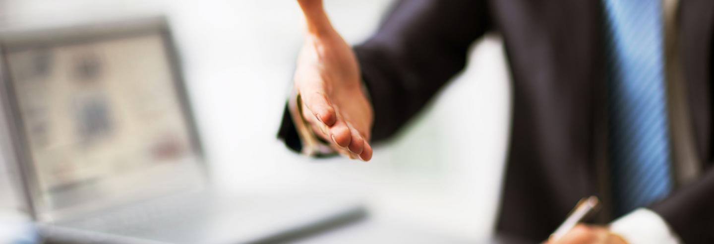 Man in zakelijke kleding steekt hand uit naar zijn gesprekspartner.