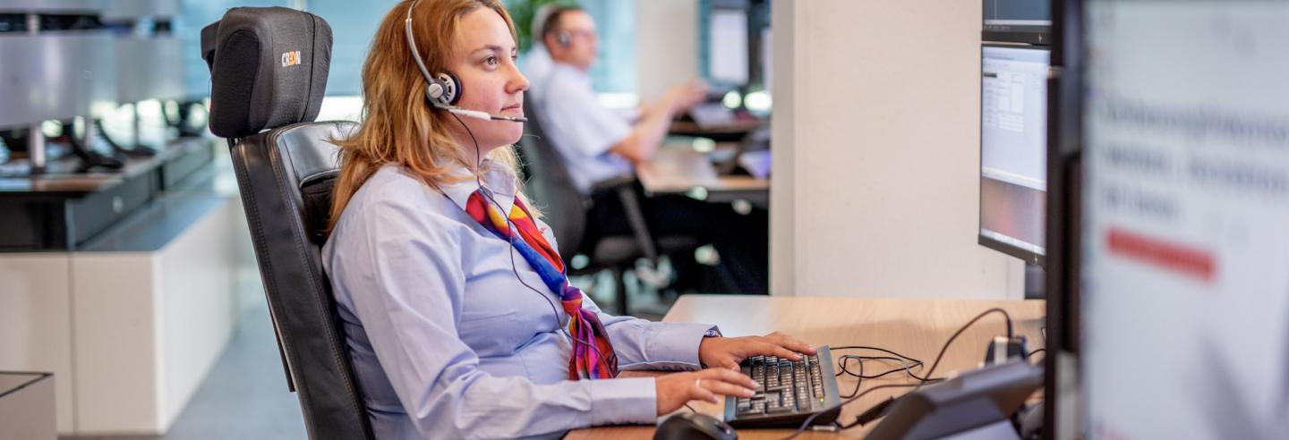 Vrouwelijke Trigion collega monitort de situatie achter haar beeldschermen.