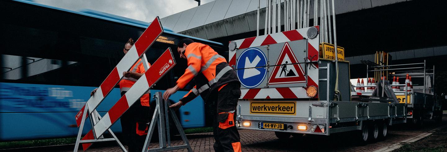 Mannelijke verkeersbegeleider plaatst een verkeerdbord op straat.