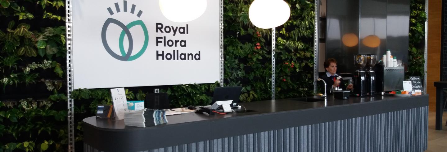 Afbeelding van de receptie in de vorm van een lange bar met daarachter een scherm met de naam Royal Flora Holland