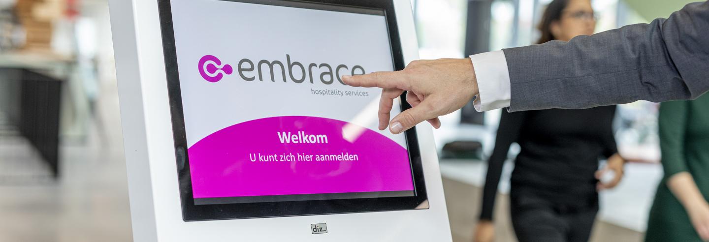 Hand reikt uit naar aanmeldpilaar waarop het logo van Embrace staat vertoond.