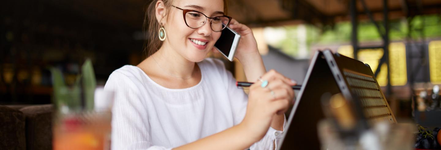 Vrouw is aan het telefoneren en tevens aan het werk achter haar laptop