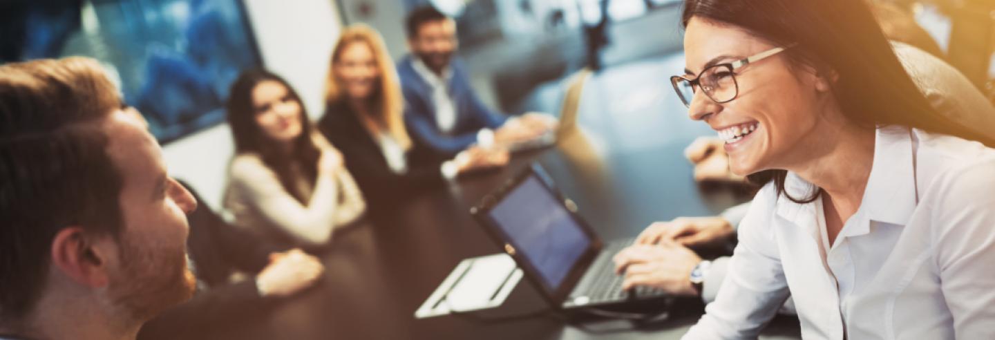 Groep collega's die met veel enthousiasme vergaderen aan een lange vergadertafel