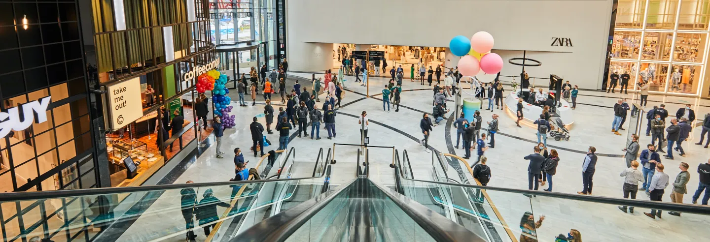 Een overzichtfoto van een ruime moderne winkelruimte met daarin winkelend publiek