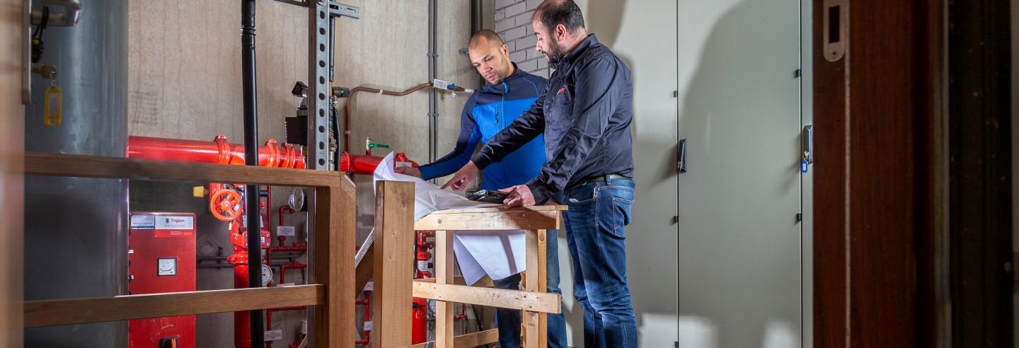 Twee mannelijke Breijer medewerkers spreken plannen door in werkruimte