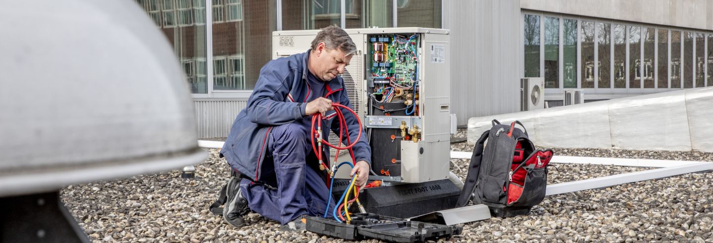 Mannelijke monteur aan het werk aan de kast van de airco.