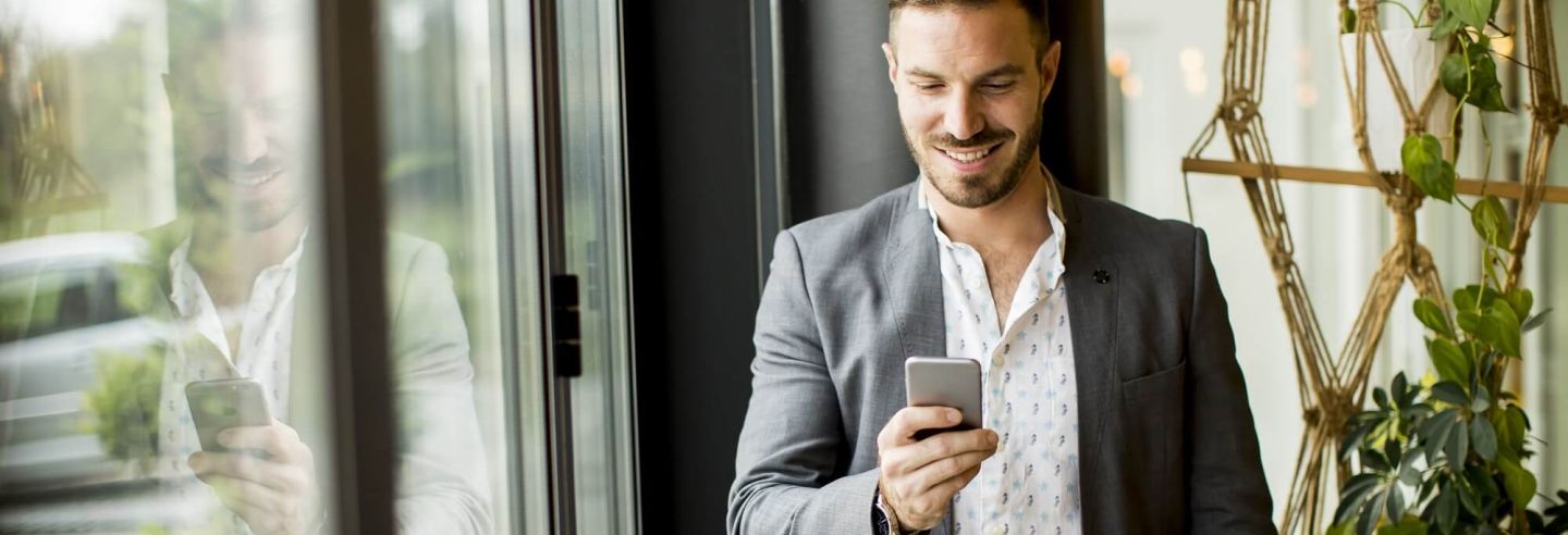 Medewerker die al lopende op zijn telefoon kijk die hij in zijn hand heeft.