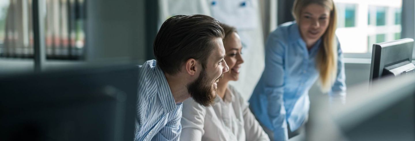 drie projectmanagers met elkaar in gesprek aan bureau kijkend naar beeldscherm.