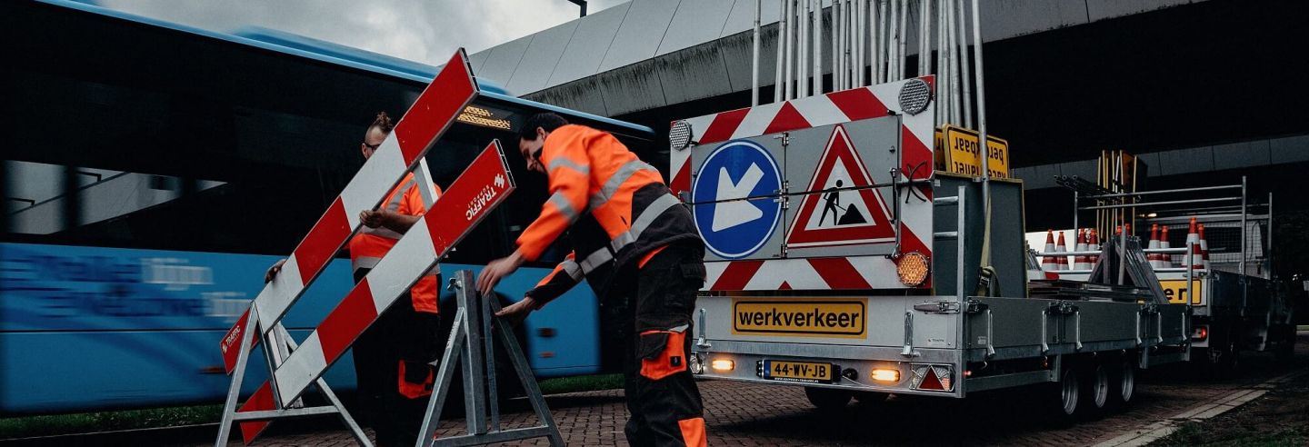 Mannelijke verkeersbegeleider plaatst een verkeerdbord op straat.