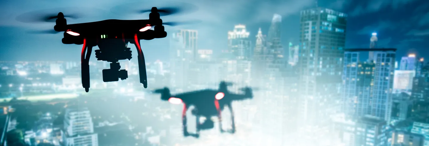 Twee drones die in de avond vliegen over een complex.