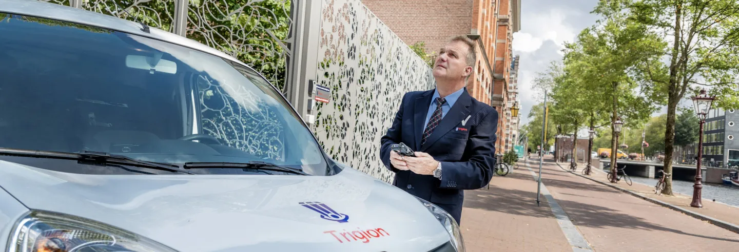 Beveiliger van Trigion arriveert bij melding en staat naast dienstauto.