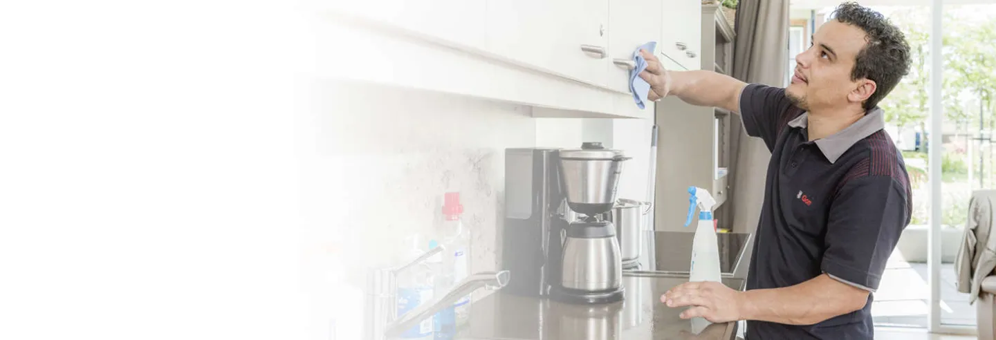 Schoonmaker van Gom maakt een keukenblad en apparatuur hygiënisch schoon.
