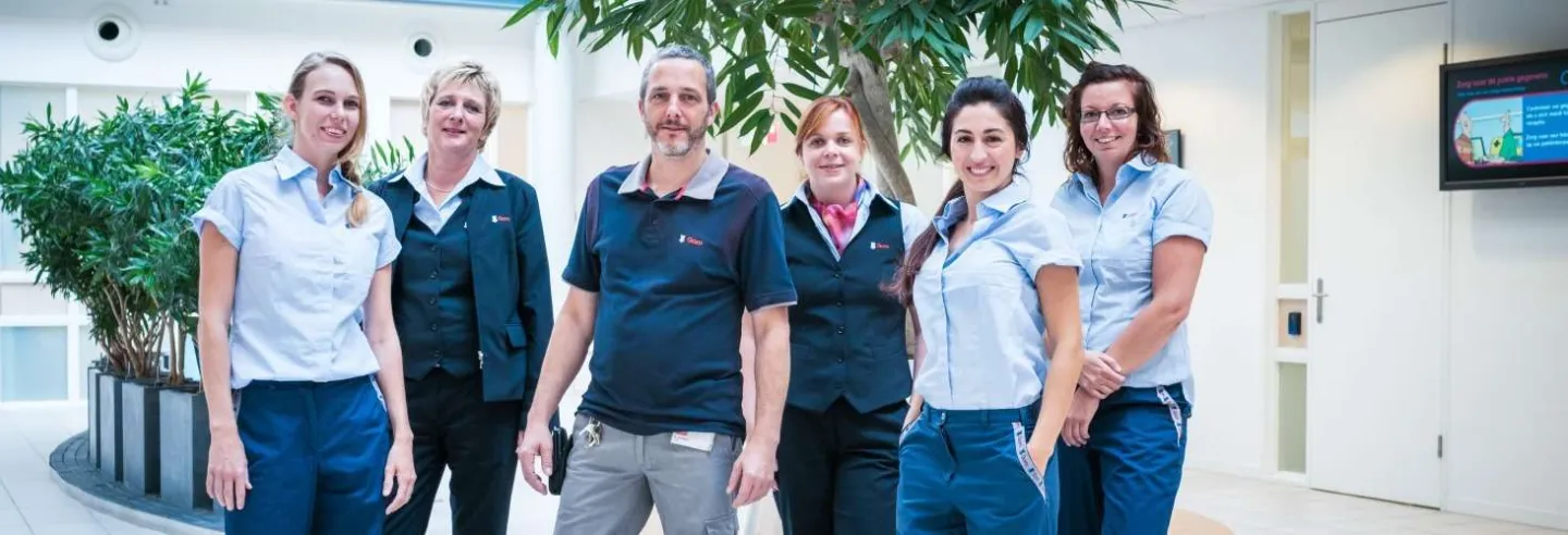 Team van Gom-medewerkers in uniform poseert samen in een lichte, groene werkomgeving.