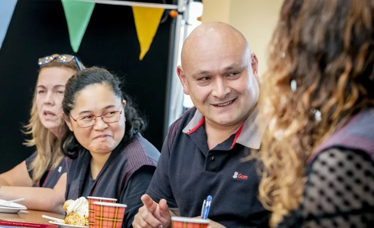 schoonmaakmedewerkers zitten aan tafel en praten lachend met elkaar