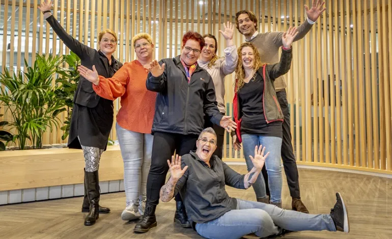 5-tal lachende en juichende schoonmaakmedewerkers met hun leidinggevenden