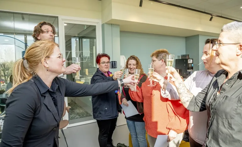 5-tal schoonmaakmedewerkers proosten met hun 2 leidinggevenden