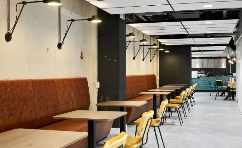 Moderne kantoorruimte met moderne banken en tafels langs muur