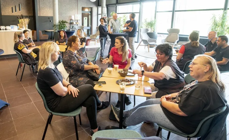 Een groep schoonmaakmedewerkers zitten verdeeld aan tafeltjes