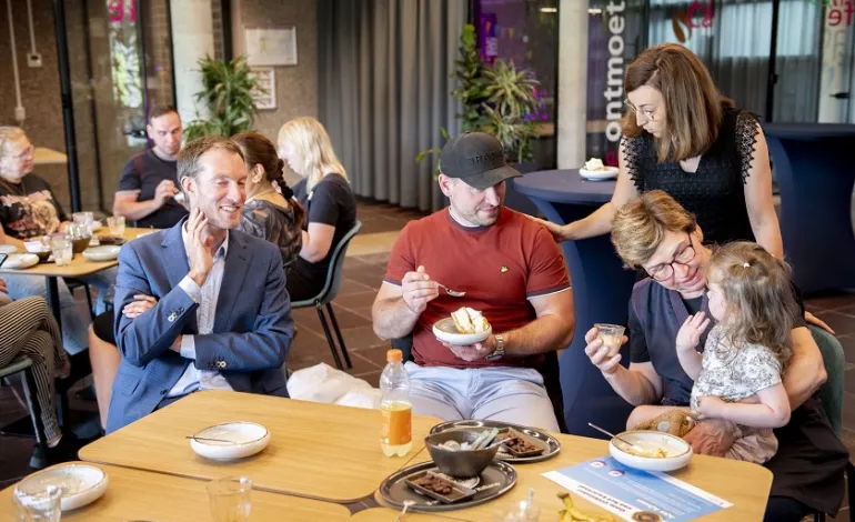 schoonmaakster Ajsa zit samen met haar kleinkind op schoot en eet samen met wat collega's taart