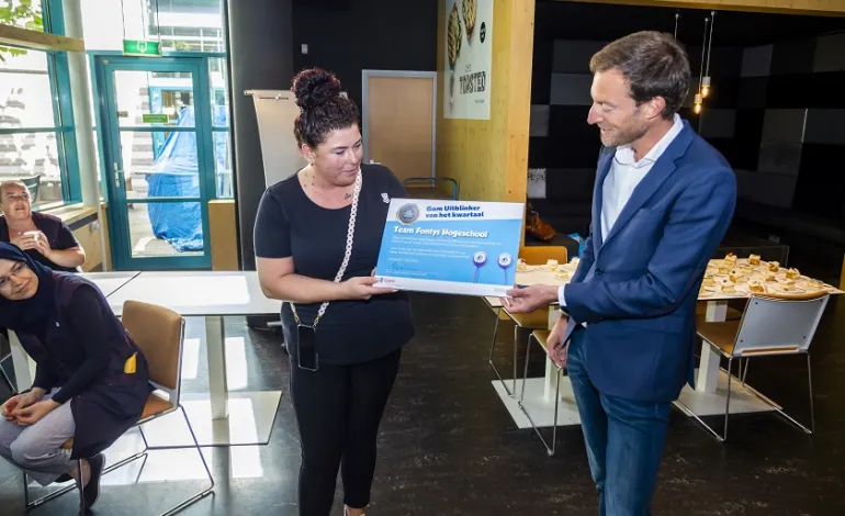 BU directeur Jeroen rijkt de Gom Uitblinker oorkonde uit aan een vrouwelijke medewerkster
