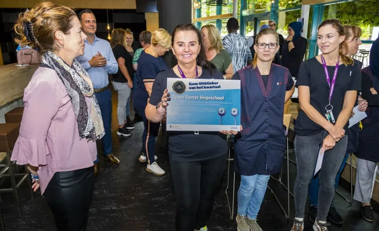 Enkele schoonmaakmedewerkers die trots de oorkonde tonen