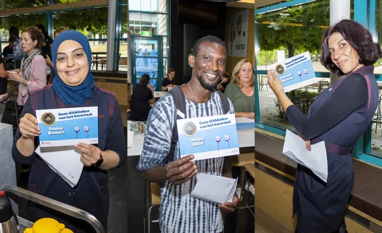 drie schoonmaakmedewerkers die trots hun oorkonde omhoog houden