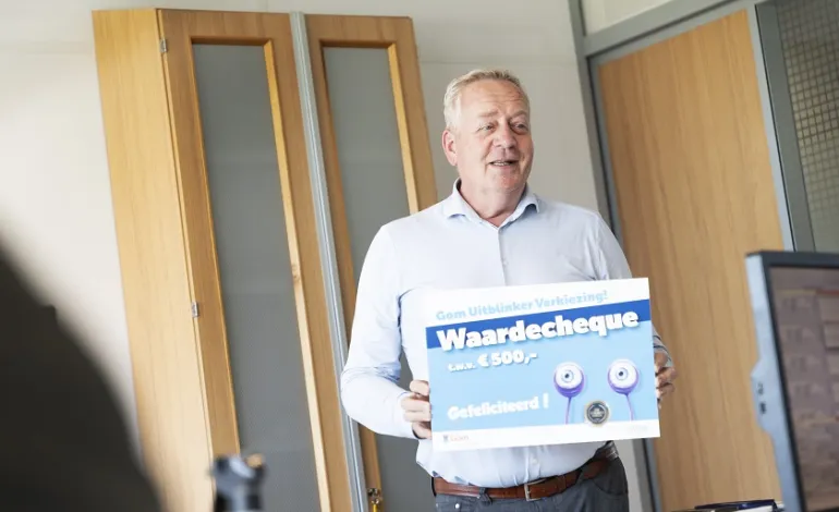 business unit directeur Peter Hoeijmans houdt de waardecheque van de Gom Uitblinker omhoog.