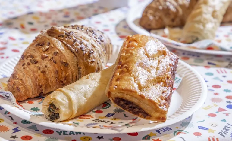 een croissantje, een saucijzenbroodje en een Turks broodje op een bordje