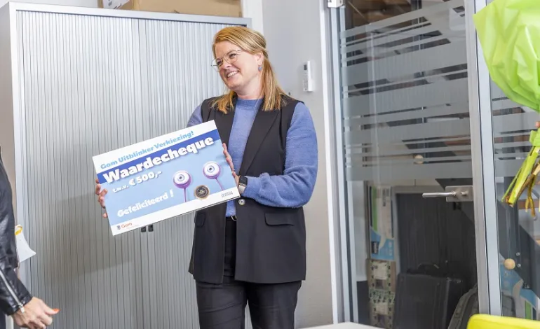 Winnaar Gom Uitblinker houdt de waardecheque van 500 euro omhoog