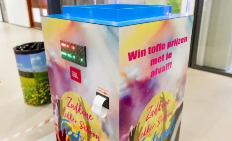vierkante gekleurde doos waar afval ingegooid kan worden en waar mensen een bonnetje voor terugkrijgen waar ze prijzen mee kunnen winnen.