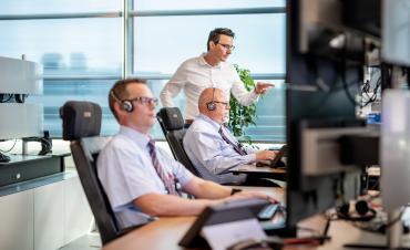 Twee mannen kijken op een computerscherm om op afstand bruggen, wegen en sluizen te bedienen.