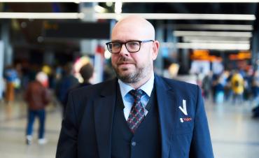 Mannelijke beveiliger in uniform loopt in de centrale hal van de Jaarbeurs Utrecht.