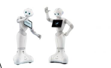 Drie witte robots met blauwe ogen genaamd Pepper, zij hebben een iPad voorop voor informatie op te lezen.