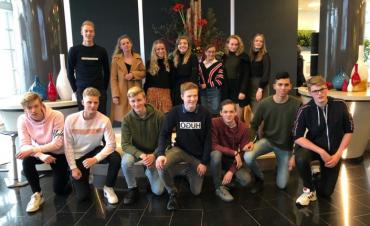 Groep jongeren geposeerd voor een groepsfoto in de hal van het hoofdkantoor van Facilicom Group in Schiedam.