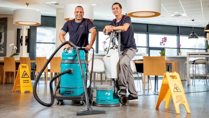 2 medewerkers van Gom Specialistische Reiniging poseren met een waterzuiger en boenmachine