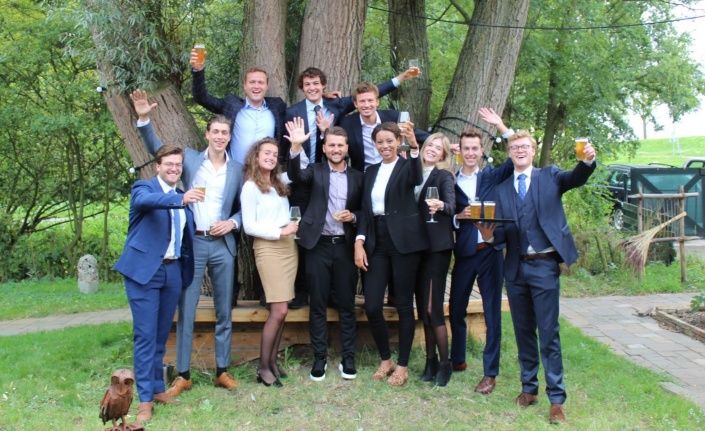 een groep van 11 trainees die voor een boom staan