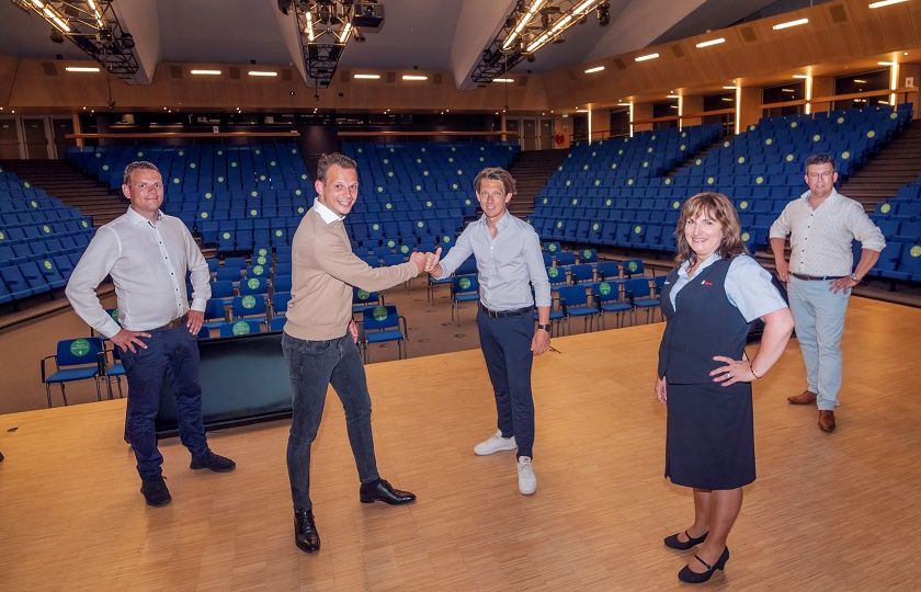 5 personen staan op het podium van een collegezaal van de TU Delft; 2 mannen geven elkaar een boks