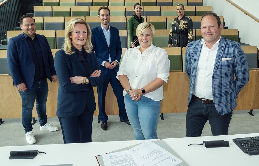 7 personen van zowel Gom als Fontys kijken lachend in de camera na ondertekening van het schoonmaakcontract