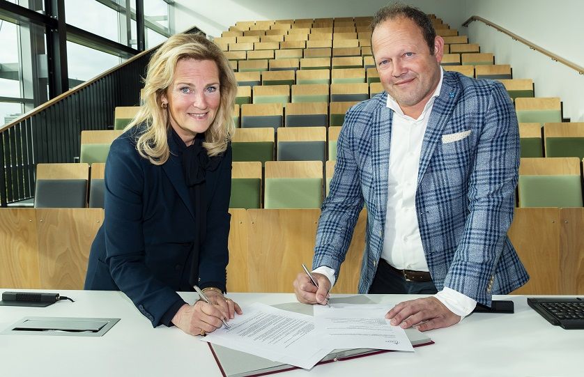 Monique Peels, Directeur Huisvesting & Facilitair Zaken (Fontys) en Barry van de Velde, Sales directeur (Gom) ondertekenen het schoonmaakcontract in een collegezaal