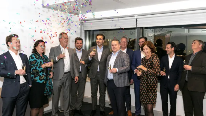 Bestuurders en medewerkers van Gom en Degenaar Gevelonderhoud vieren de overname met champagne en confetti in een feestelijke setting.