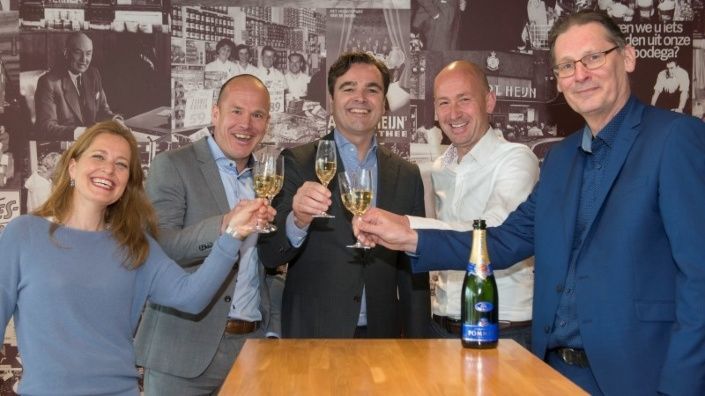 Een groepje van 5 personen proost met champagne na ondertekening contract