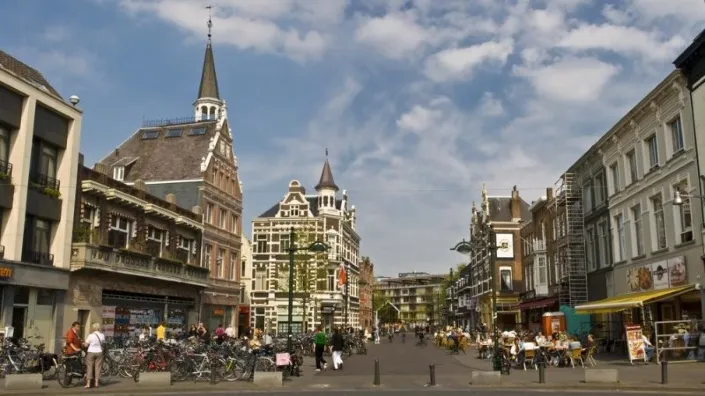 Drukke binnenstad van Breda met historische gebouwen, terrasjes en fietsers op straat.