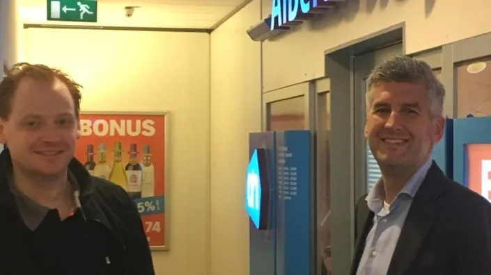 Peter Roeleveld en Michiel Kooijman van Gom bij de ingang van een Albert Heijn-filiaal, in gesprek over de samenwerking met Ahold Delhaize.