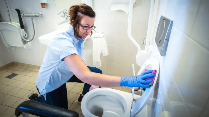 Schoonmaakmedewerker van Gom Zorg maakt een toilet grondig schoon in een sanitaire ruimte van de Radiotherapiegroep Deventer, als onderdeel van 24-uurs schoonmaak met probiotica.