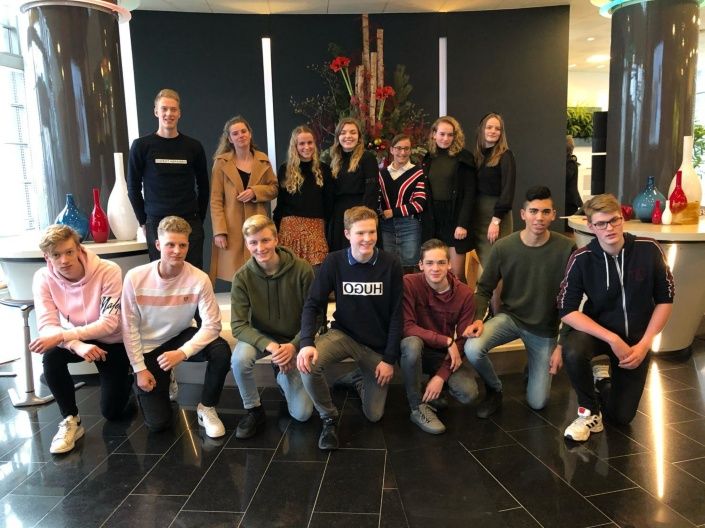 Groep jongeren geposeerd voor een groepsfoto in de hal van het hoofdkantoor van Facilicom Group in Schiedam.