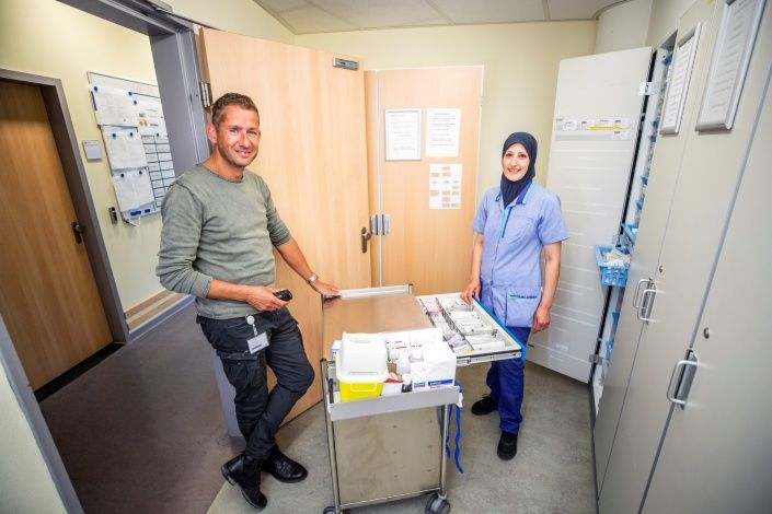 Philip Vriend van het Dijklander Ziekenhuis en Kafa el Akhras van Gom Zorg staan in de voorraadkamer met een kar materialen